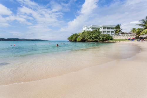a beach with people in the water and a building at Grand Palladium Jamaica Resort & Spa All Inclusive in Lucea
