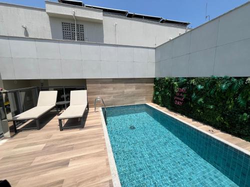 Una piscina con dos sillas al lado de un edificio. en Apart Hotel Praia Ingá Quarto, Sala, 2 Varandas e Vista Parcial MAC, en Niterói