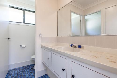 ein weißes Badezimmer mit Waschbecken und Spiegel in der Unterkunft Barrels at Boomerang in Boomerang Beach