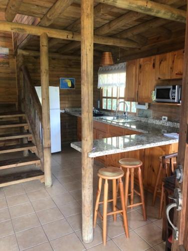 a kitchen with a counter and stools in a cabin at San Luis cabin in Grecia