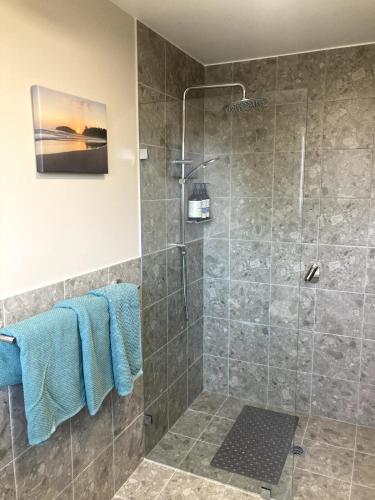 a bathroom with a shower with blue towels at Jimmies on Saltwood in Tomakin
