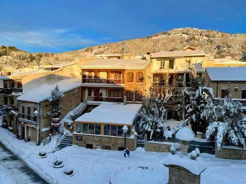 un bâtiment avec de la neige sur le sol devant lui dans l'établissement El Encanto de Miraflores, à Miraflores de la Sierra