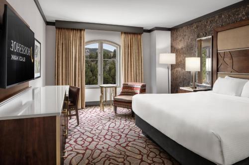 ein Hotelzimmer mit Bett, Schreibtisch und Fernseher in der Unterkunft Horseshoe Black Hawk, A Caesars Destination in Black Hawk