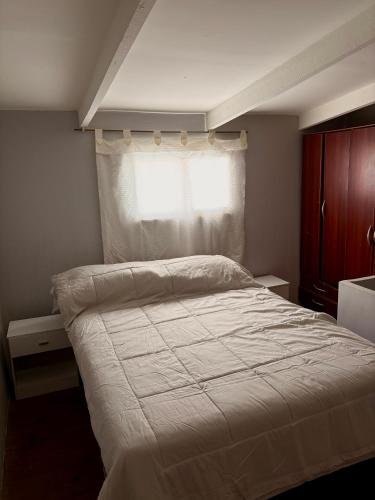 ein Schlafzimmer mit einem weißen Bett mit einem Fenster in der Unterkunft Departamento simple y cómodo en Cipolletti in Cipolletti