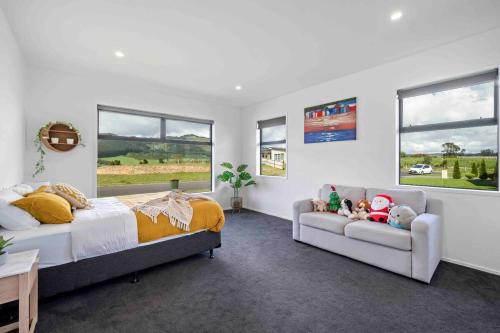 une chambre avec deux lits et un canapé et des fenêtres dans l'établissement 6 Bedrooms Hillside Lodge, à Rotorua