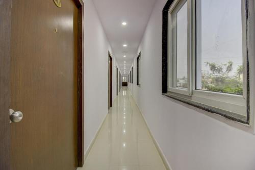 OYO Flagship Grand Mythri في Maula Ali: ممر طويل مع جدران بيضاء ونافذة