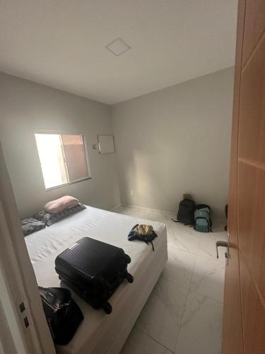 ein Schlafzimmer mit einem Bett mit einem Koffer drauf in der Unterkunft Casa temporada in Cabo Frio