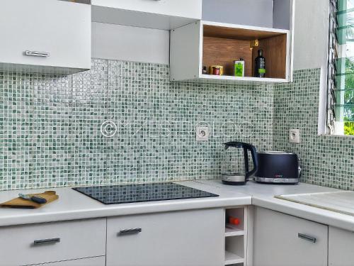 una cucina con armadi bianchi e piastrelle verdi di OFFRE NOËL ! Pied-à-Terre des Professionnels & Familles - Aéroport 12 min a Baie-Mahault