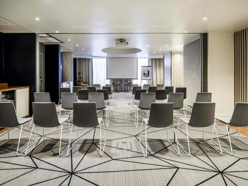 a conference room with chairs and a projection screen at Novotel Den Haag City Centre in The Hague
