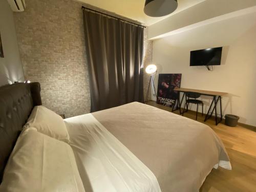a bedroom with a bed and a desk with a television at Maison Voyage Messina in Messina