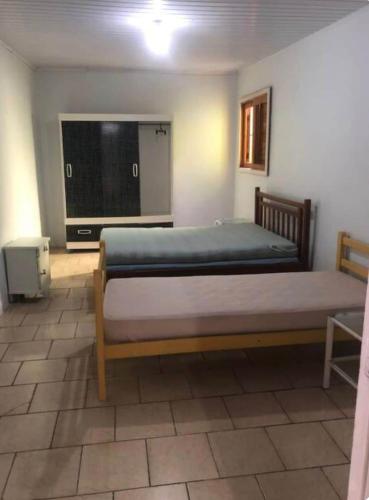 a bedroom with a large bed and a television at Casa de praia - 2 quadras do mar in Arroio do Sal