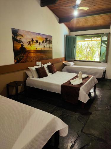 a hotel room with two beds and a window at Hotel Trevo do Porto in Porto Seguro