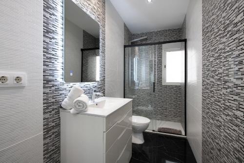 a bathroom with a sink and a toilet and a mirror at PLAYA a 3 minutos Parking barbacoa Apartamento en Castelldefels in Castelldefels