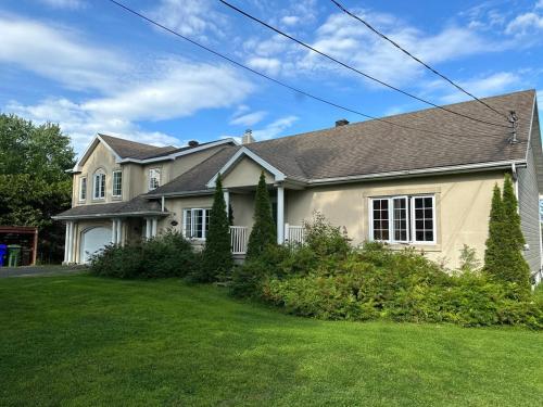 a white house with a green yard at Havre du lac magog in Sainte-Catherine-de-Hatley