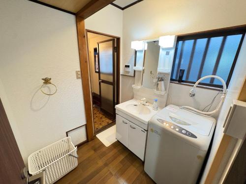 a bathroom with a white sink and a mirror at Guesthouse すえ in Mashizume