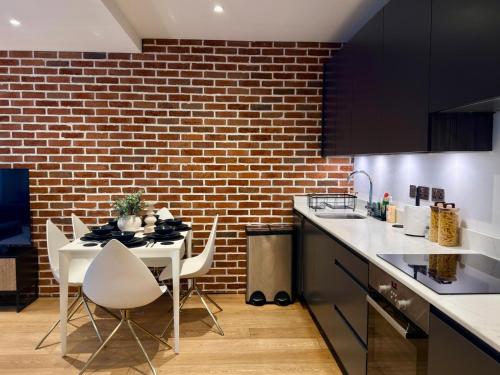a kitchen with a white table and a brick wall at Modern & Luxurious 2-bed by ABBA, O2 & Canary Wharf in London