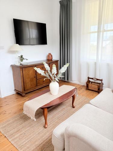 a living room with a vase of flowers on a coffee table at The Kandos Nook- Adventure, Wine & Country Charm in Kandos