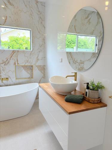 ein Badezimmer mit Waschbecken, Badewanne und Spiegel in der Unterkunft The Kandos Nook- Adventure, Wine & Country Charm in Kandos
