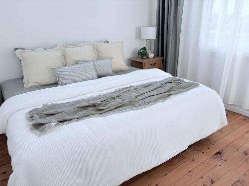 ein weißes Bett in einem Schlafzimmer mit Holzboden in der Unterkunft The Kandos Nook- Adventure, Wine & Country Charm in Kandos