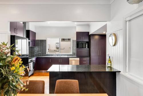 eine Küche mit lila Schränken und einer schwarzen Arbeitsplatte in der Unterkunft Botanic Breeze! Opposite Queens Park! in Toowoomba