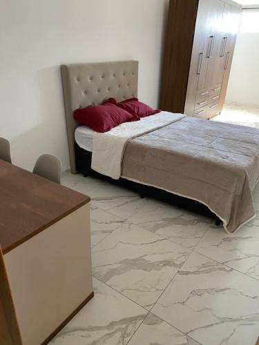 a bedroom with a bed with red pillows on it at Kitnet Centro da Cidade in São Bento do Sapucaí