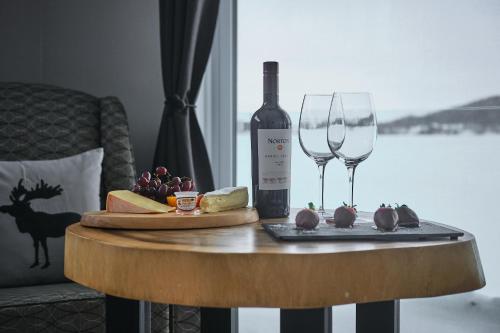 a table with a bottle of wine and a glass at Étoile du Lac Lyster - Spa & Vue sur le Lac in Coaticook