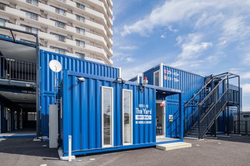 a blue building with a staircase next to a building at HOTEL R9 The Yard Katsura in Katsuura