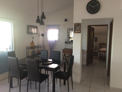 jadalnia ze stołem, krzesłami i zegarem w obiekcie Apartment Gigi w mieście Jadranovo