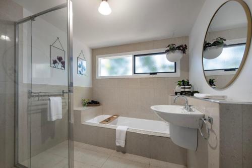 a bathroom with a tub and a sink and a mirror at Wayward Cottage in Daylesford