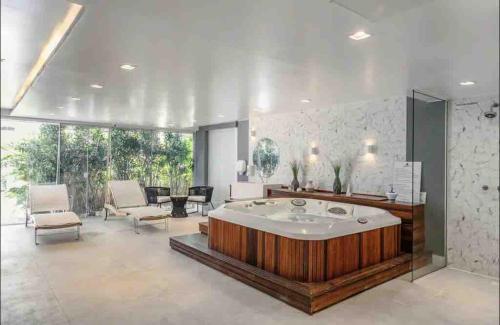 a large bathroom with a tub and a table and chairs at Refúgio VIP Pé na Areia no Campeche - Piscina, Sauna e Academia até 08 pessoas in Florianópolis