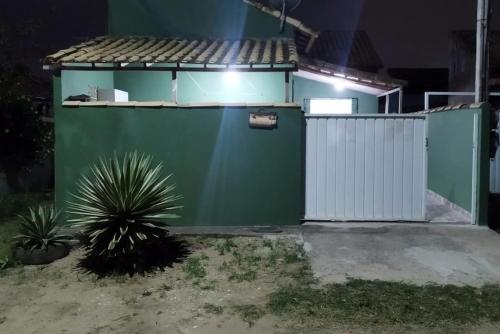 un bâtiment vert avec un portail blanc et une plante dans l'établissement Casa de praia Região dos Lagos - CASA VERDE - Unamar - Cabo Frio RJ, à Cabo Frio