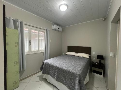 ein Schlafzimmer mit einem Bett und einem Fenster in der Unterkunft Residencial Elsa Tarcila in Bombinhas