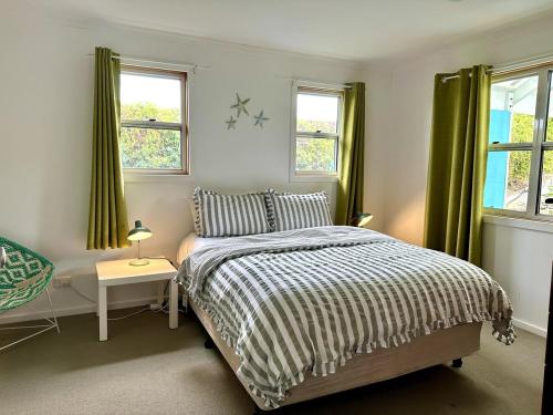 Un dormitorio con una cama y dos ventanas en Dunes Aqua at Robe, en Robe