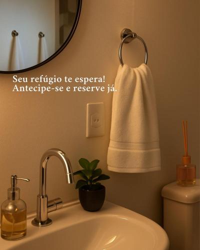 a bathroom with a sink and a mirror and a towel at Sana Suítes in Macaé