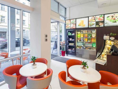 two tables and orange chairs in a restaurant at Ibis Praha Wenceslas Square in Prague