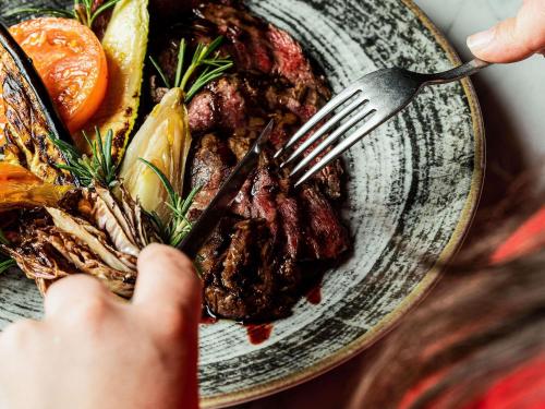 une personne mangeant une assiette de nourriture avec une fourchette dans l'établissement Hotel Mercure Roma Corso Trieste, à Rome