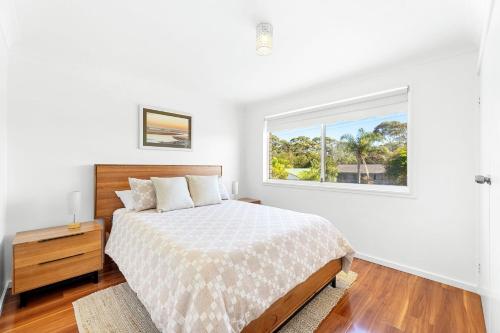 a white bedroom with a bed and a window at Kianga Lodge, 1 Sunset Blvd in Kianga