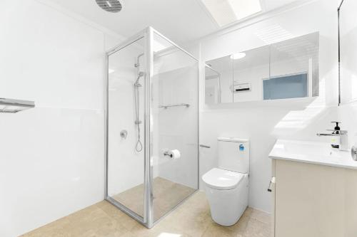 a bathroom with a shower and a toilet and a sink at Kianga Lodge, 1 Sunset Blvd in Kianga