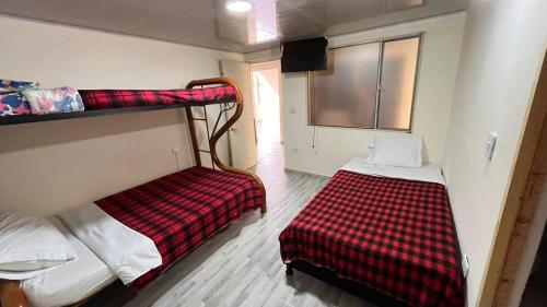 une chambre avec deux lits superposés et une couverture à carreaux rouges et blancs dans l'établissement Hostal Dulcinea, à Tocancipá