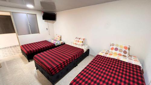 une chambre avec deux lits et une télévision à écran plat dans l'établissement Hostal Dulcinea, à Tocancipá