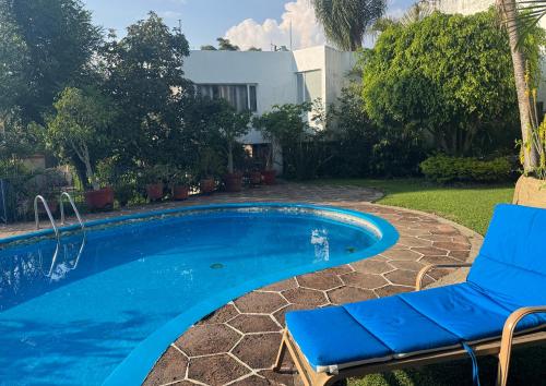 a swimming pool with a blue chair and a swimming pool at Casa con hermoso jardín y terraza in Cuernavaca