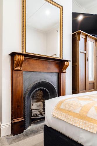 a bedroom with a fireplace with a mirror on the wall at Seaview House in Queenscliff