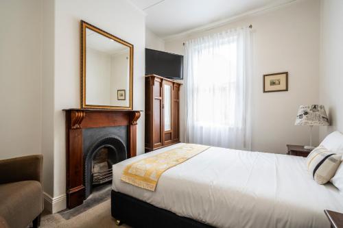 a bedroom with a bed and a mirror and a fireplace at Seaview House in Queenscliff