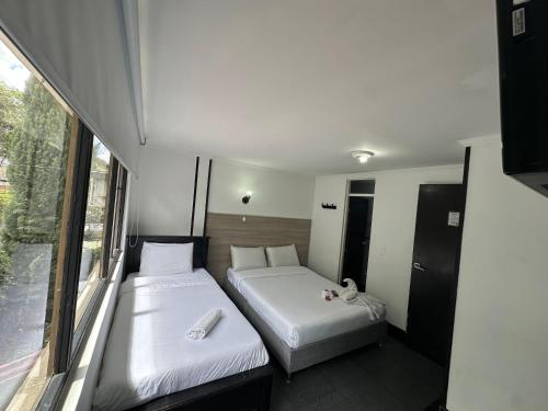 two beds in a small room with a window at Latín Boutique in Bogotá