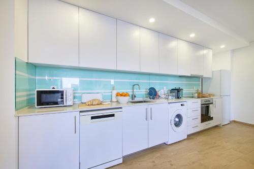 eine Küche mit weißen Schränken und einer Waschmaschine und einem Trockner in der Unterkunft Large Group Beach Stay, by TimeCooler in Setúbal