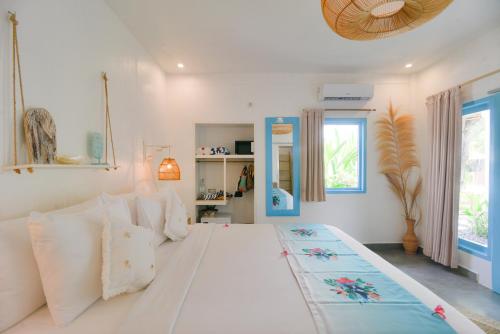 a bedroom with a large white bed with white pillows at The Koho Air Hotel in Gili Islands