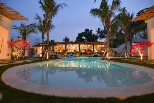 una piscina davanti a una casa con palme di The Koho Air Hotel a Gili Air