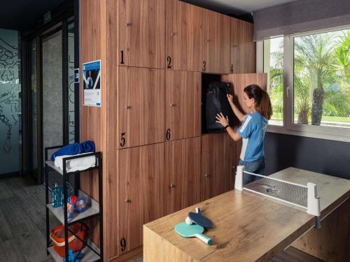 Una mujer parada en una habitación mirando una pared. en Ibis Budget Málaga Aeropuerto Avenida de Velazquez, en Málaga