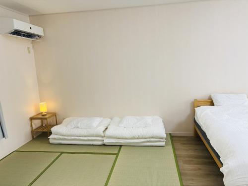 um quarto com duas camas sentadas uma ao lado da outra em Jazz 喫茶 Eju イージュ B&B em Urazoe