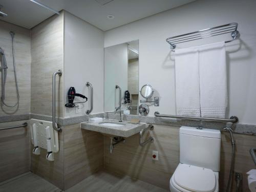 a bathroom with a toilet and a sink and a shower at Mercure Salvador Rio Vermelho in Salvador